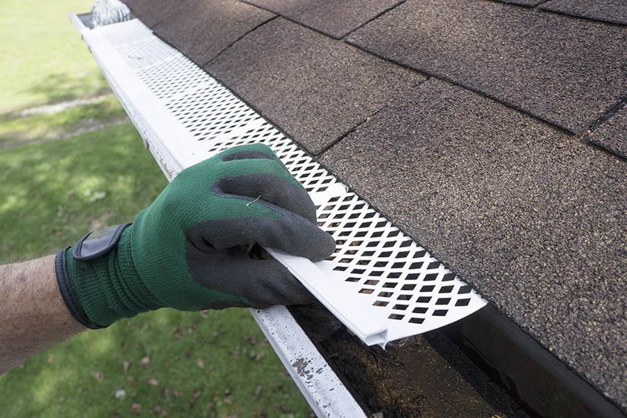 person installing guard on gutter